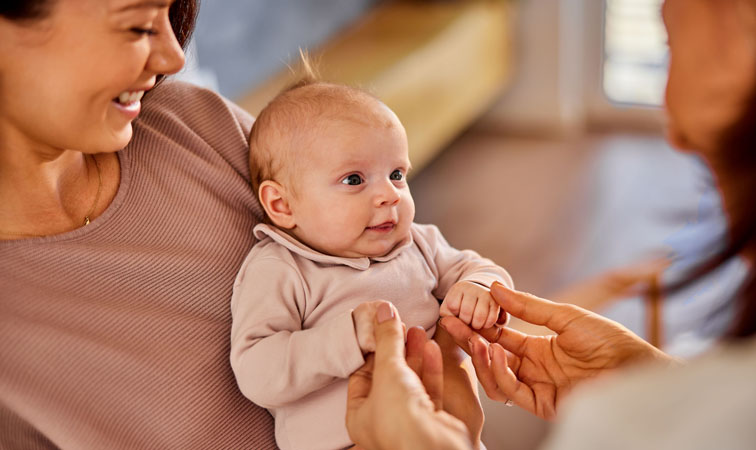 Eine Mutter hält ihr Kind auf dem Arm und spricht mit einer Fachkraft.