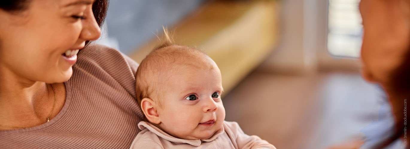 Eine Mutter hält ihr Kind auf dem Arm und spricht mit einer Fachkraft.